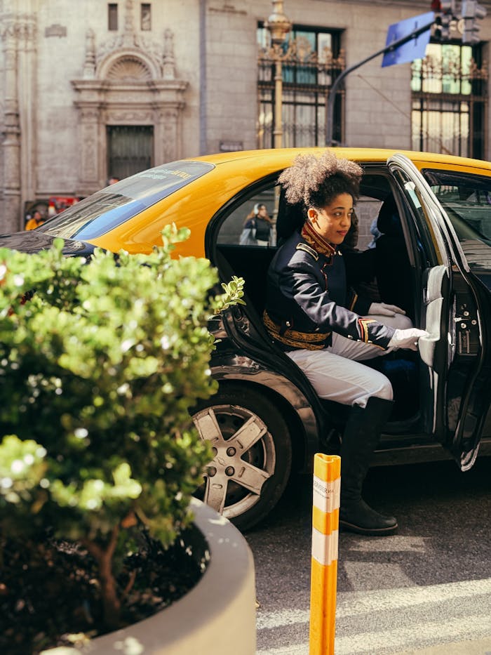 Uniformed doorman steps out of a vintage taxi on a sunny day in Buenos Aires, Argentina.